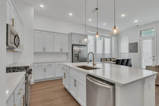 a kitchen with a sink a stove a refrigerator and white cabinets