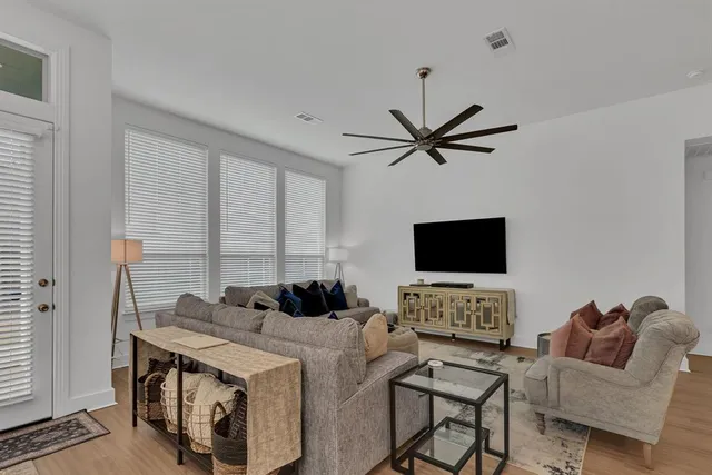 a living room with furniture a clock and a flat screen tv