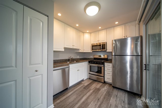 106 Gant Circle, Unit G Streamwood, IL 60107 - Photo 3 of 12 a kitchen with stainless steel appliances granite countertop a refrigerator microwave and stove