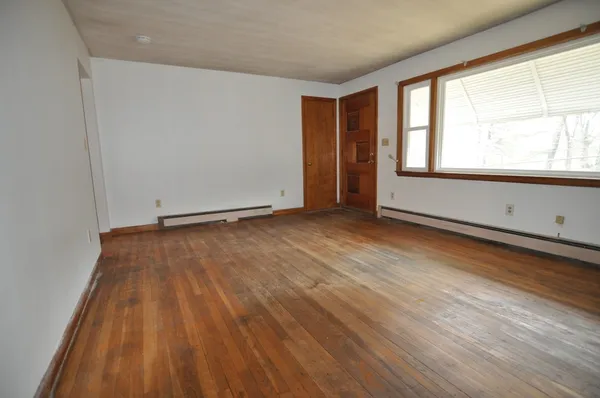 an empty room with wooden floor and windows