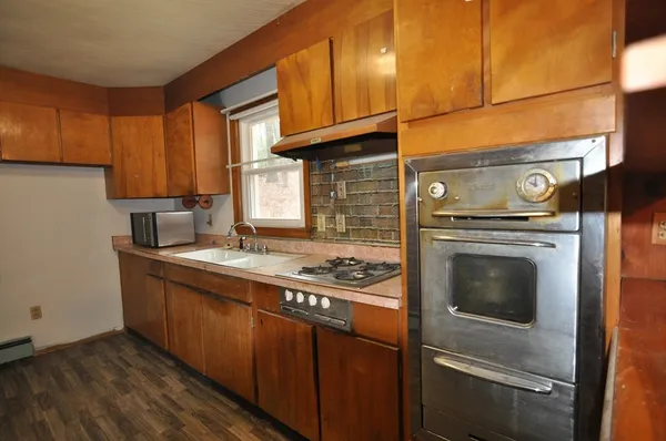 a kitchen with granite countertop a stove top oven microwave and cabinets