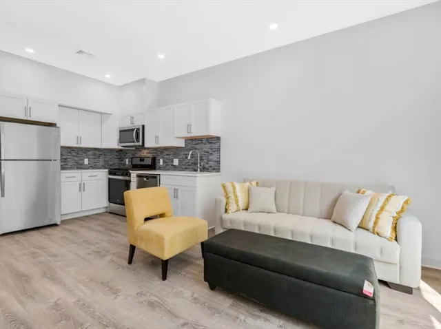 a living room with stainless steel appliances furniture and a kitchen view