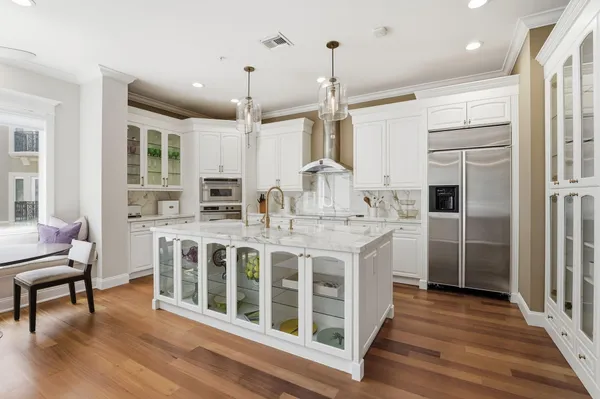 a dining room with wooden floor a chandelier a glass table and chairs