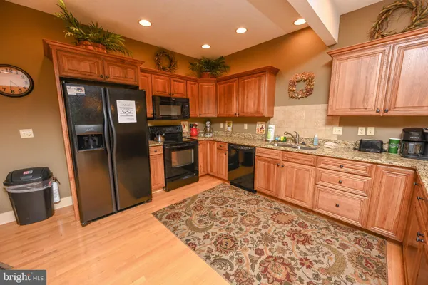 a kitchen with stainless steel appliances granite countertop a sink stove refrigerator and cabinets