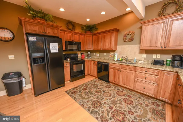 a kitchen with stainless steel appliances granite countertop a sink stove refrigerator and cabinets