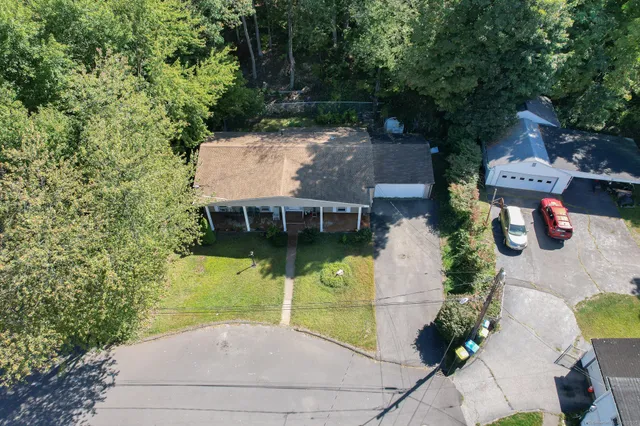 an aerial view of a house with swimming pool and large trees