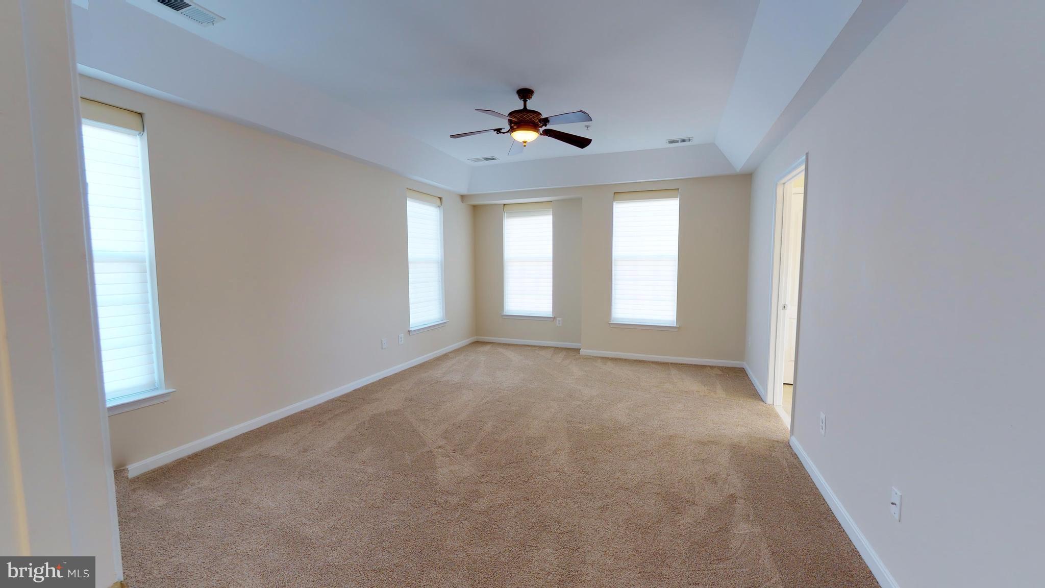8601 Roaming Ridge Way, Unit 402 Odenton, MD 21113 - Photo 11 of 30 an empty room with a ceiling fan and windows