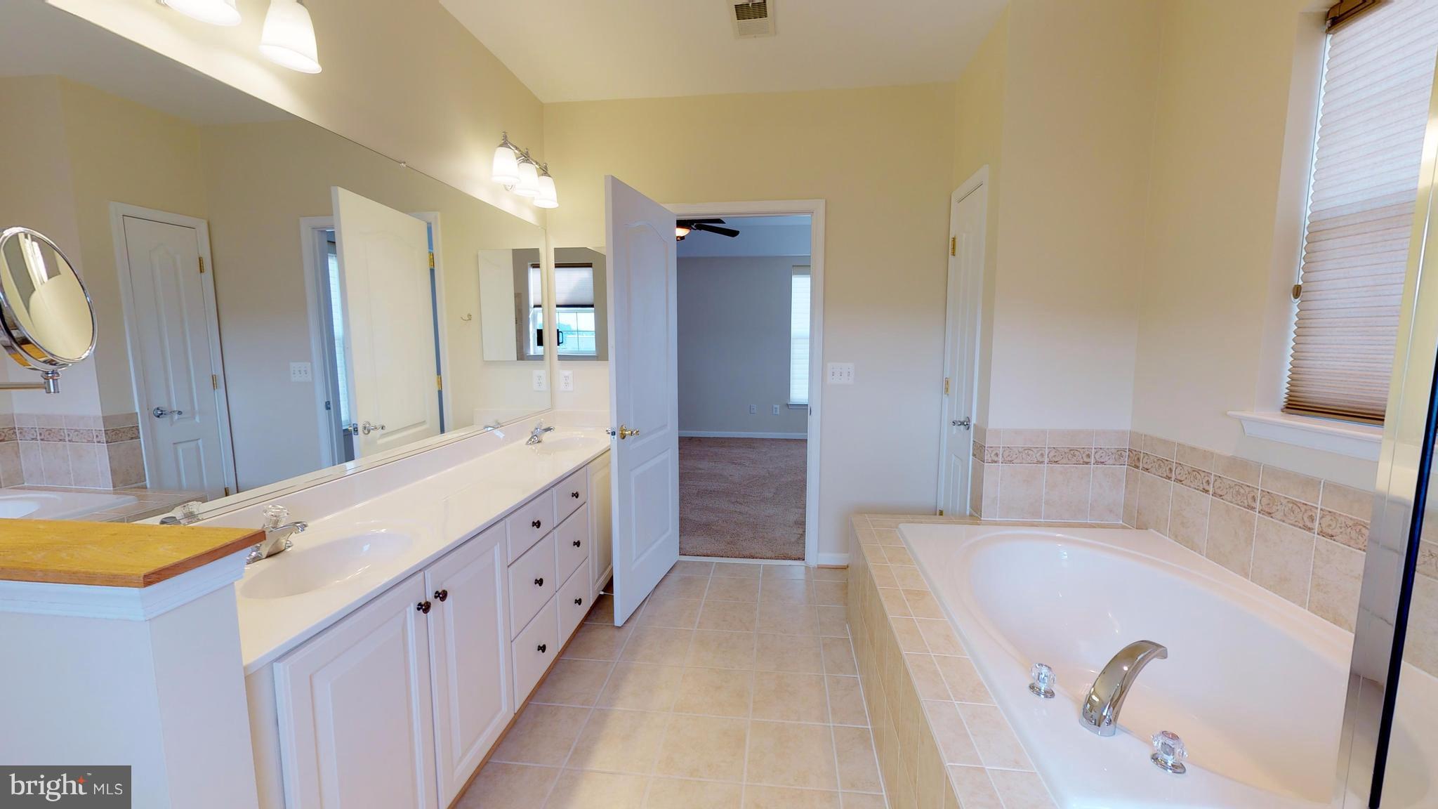 8601 Roaming Ridge Way, Unit 402 Odenton, MD 21113 - Photo 15 of 30 a spacious bathroom with a tub sink and mirror