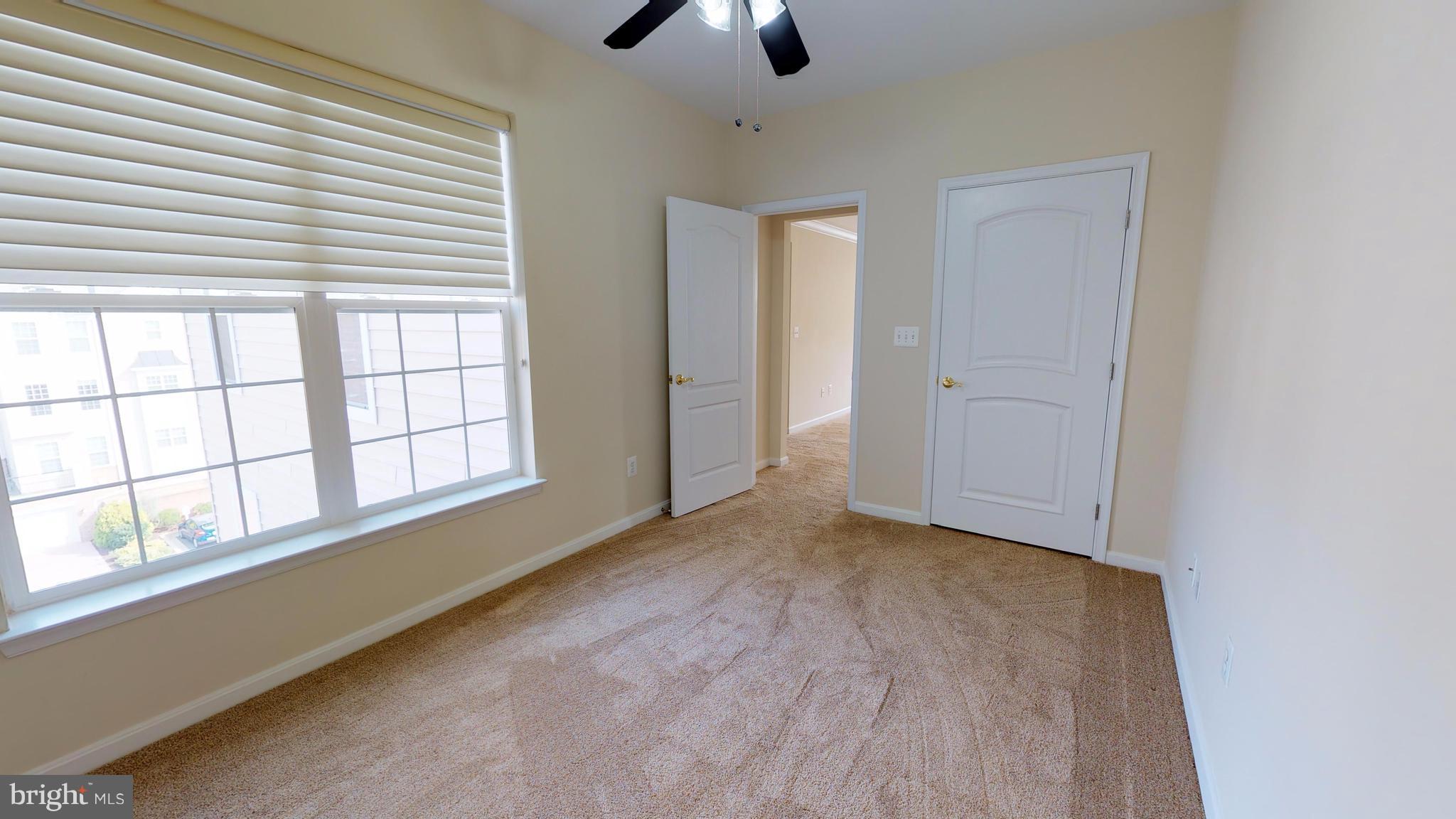 8601 Roaming Ridge Way, Unit 402 Odenton, MD 21113 - Photo 18 of 30 an empty room with chandelier fan and windows