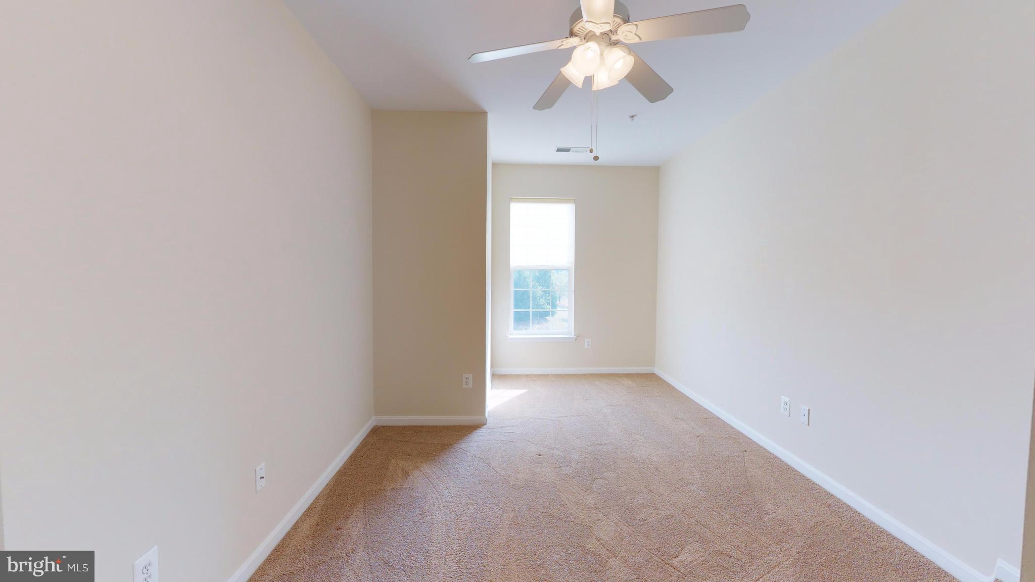 8601 Roaming Ridge Way, Unit 402 Odenton, MD 21113 - Photo 19 of 30 an empty room with a chandelier fan and windows