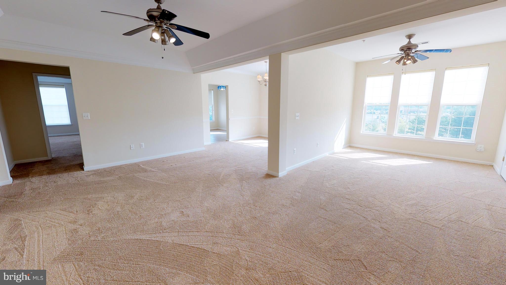 8601 Roaming Ridge Way, Unit 402 Odenton, MD 21113 - Photo 3 of 30 a view of an empty room with a chandelier fan and a window