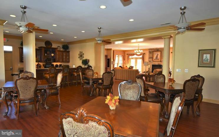 8601 Roaming Ridge Way, Unit 402 Odenton, MD 21113 - Photo 28 of 30 a living room with lots of chairs and wooden floors