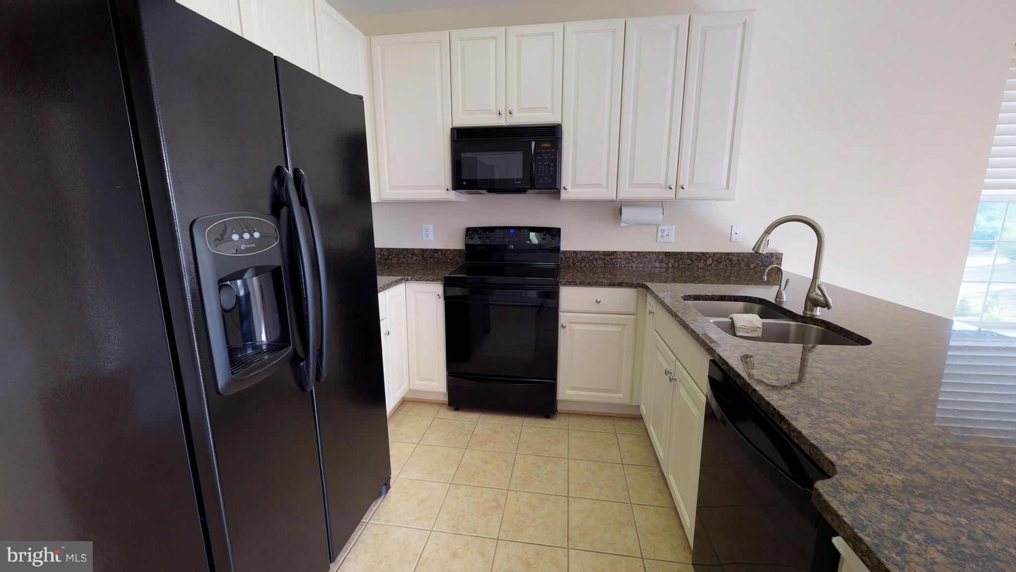 8601 Roaming Ridge Way, Unit 402 Odenton, MD 21113 - Photo 10 of 30 a kitchen with stainless steel appliances granite countertop a refrigerator stove and sink