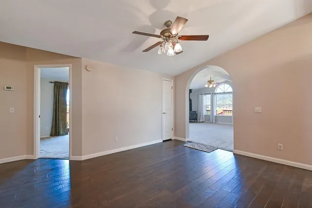 a view of a big room with wooden floor and a chandelier fan