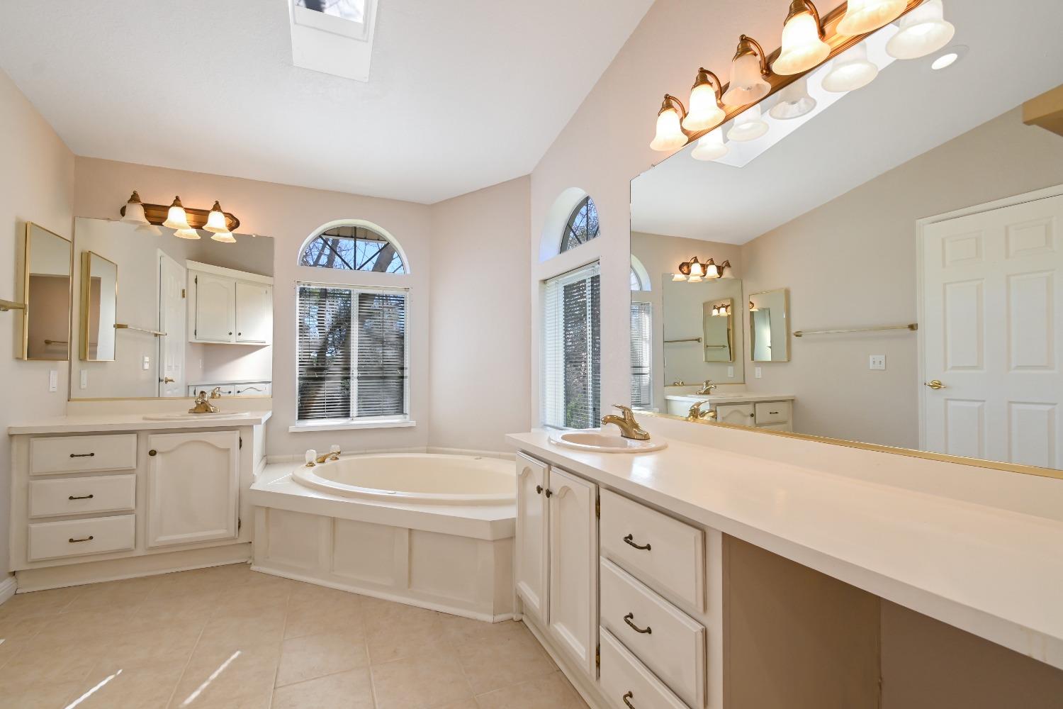 15655 County Road 45 Guinda, CA 95637 - Photo 16 of 66 a spacious en suite bathroom with a granite countertop double vanity sink a mirror a bathtub and a window