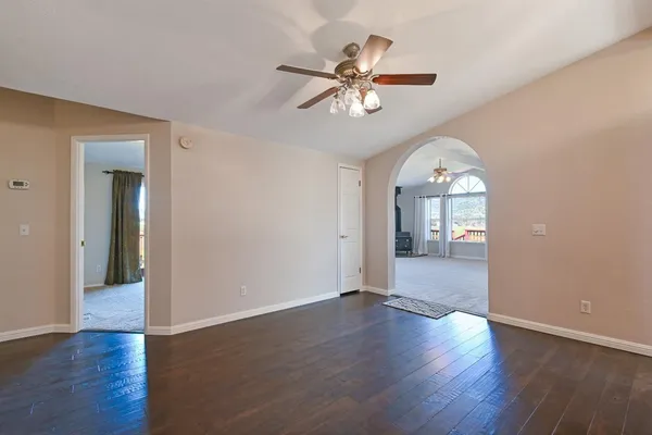 a view of a big room with wooden floor and a chandelier fan