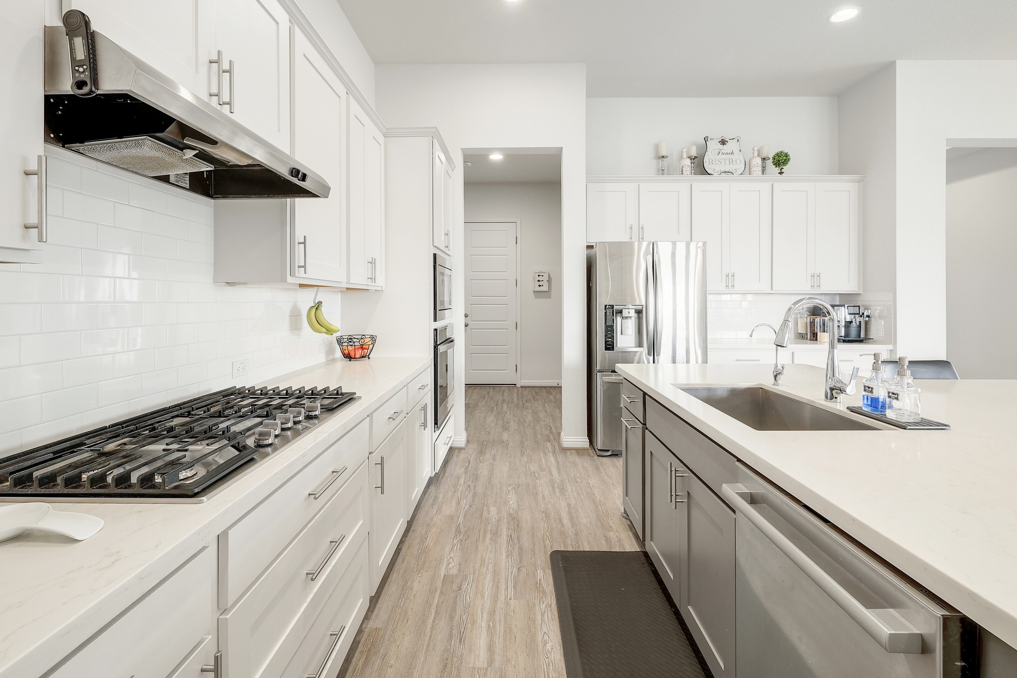 108 Argo Cove Georgetown, TX 78628 - Photo 11 of 36 Dual tone kitchen featuring light wood finished floors, dual tone cabinets, stainless steel appliances, light stone counters, and recessed lighting