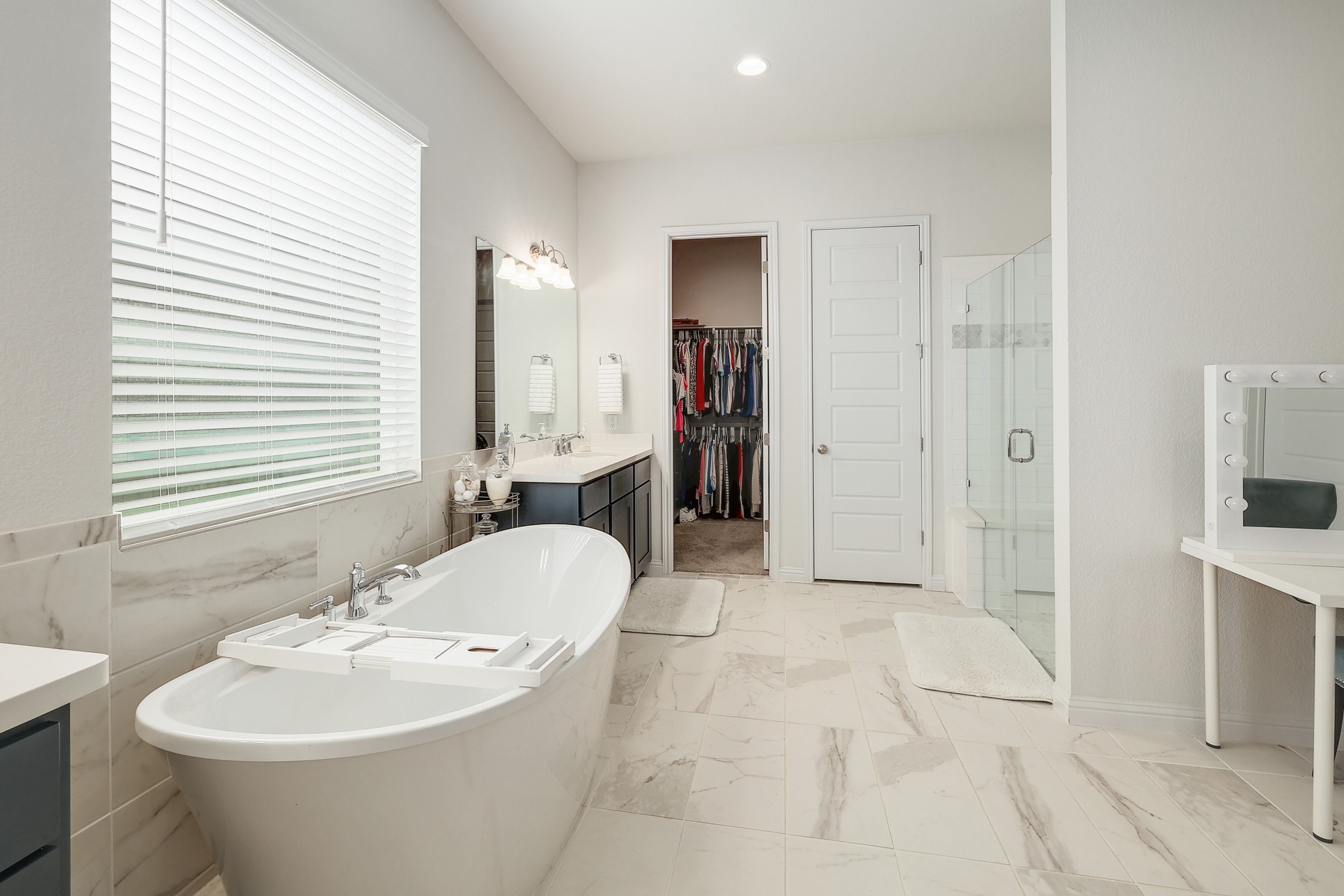 108 Argo Cove Georgetown, TX 78628 - Photo 16 of 36 Bathroom featuring vanity, a walk in closet, a freestanding bath, a stall shower, and light marble finish floors