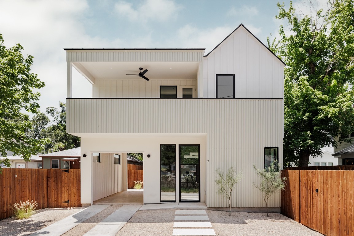 Rear view of house featuring a carport, a patio area, a balcony, and ceiling fan