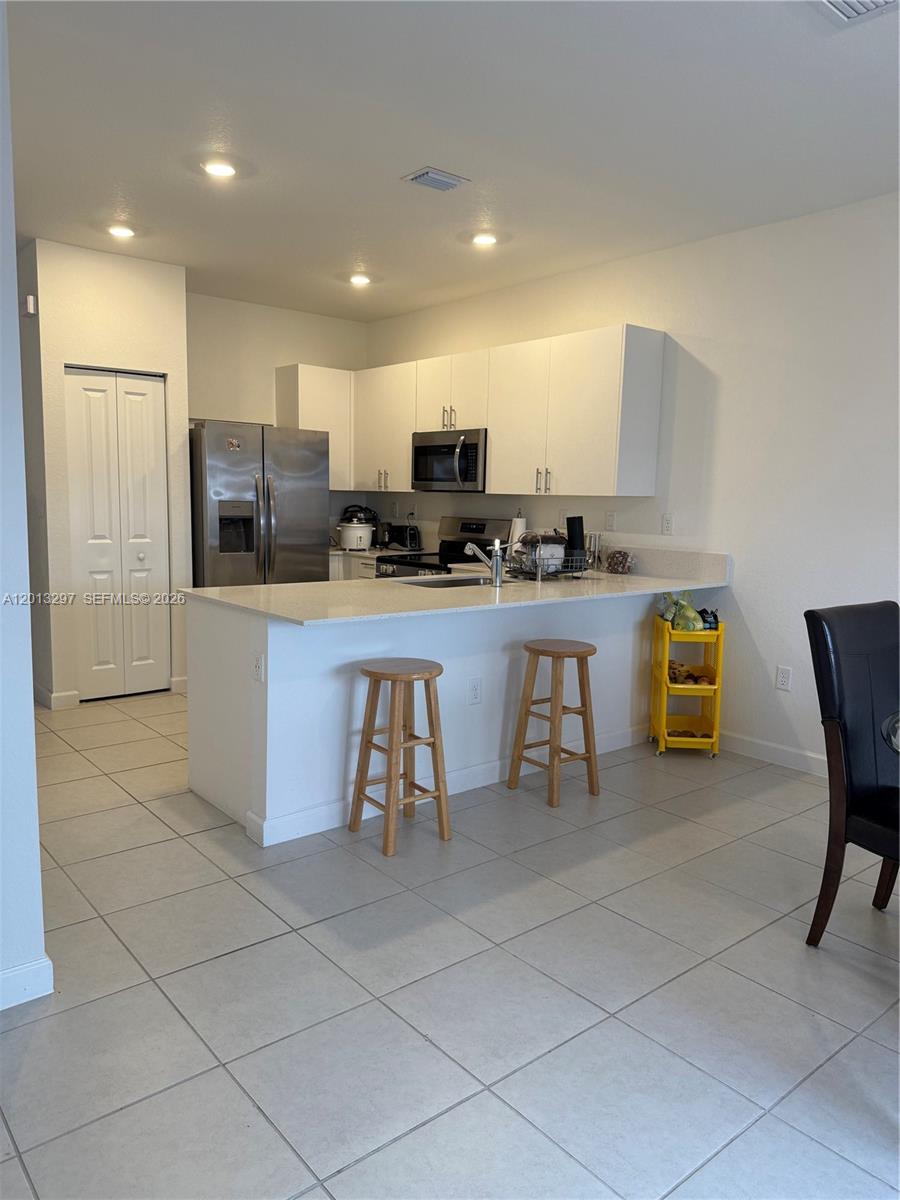 12955 Southwest 231st Terrace, Unit 12955 Miami, FL 33170 - Photo 4 of 26 a kitchen with stainless steel appliances a refrigerator and a stove top oven