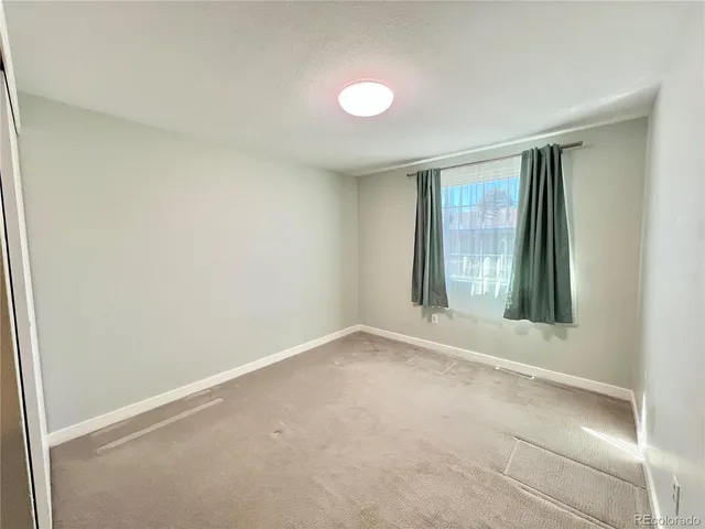 an empty room with windows and chandelier fan