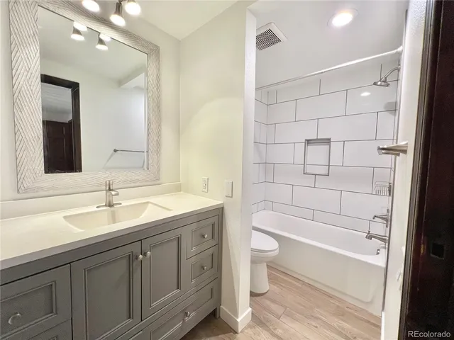 a bathroom with a granite countertop sink a toilet and bathtub
