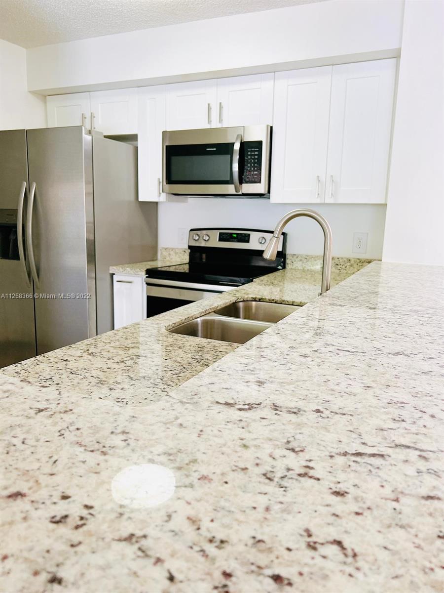 650 South Park Road, Unit 225 Hollywood, FL 33021 - Photo 8 of 26 a kitchen with kitchen island a sink stainless steel appliances and cabinets