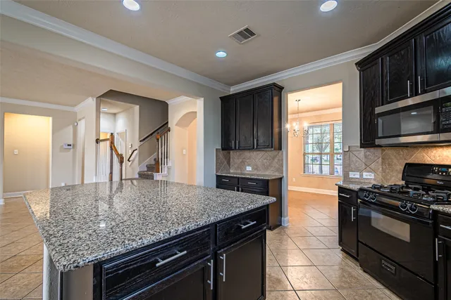 a kitchen with kitchen island granite countertop a stove and a sink