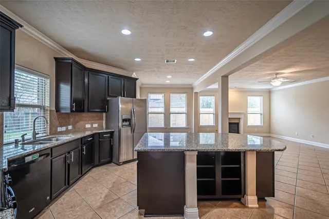 a large kitchen with granite countertop a large counter top stainless steel appliances a sink and cabinets