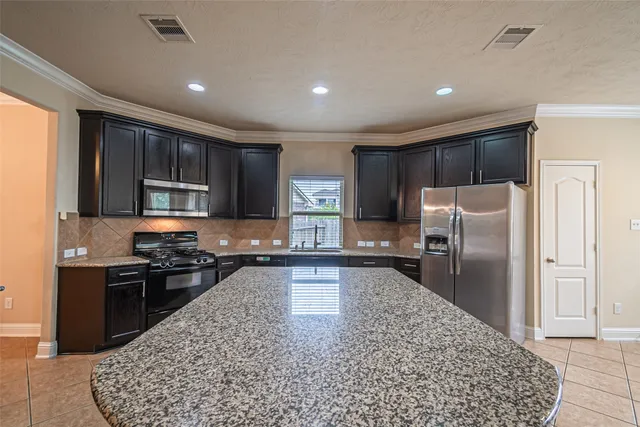 a kitchen with stainless steel appliances granite countertop a refrigerator stove microwave and sink