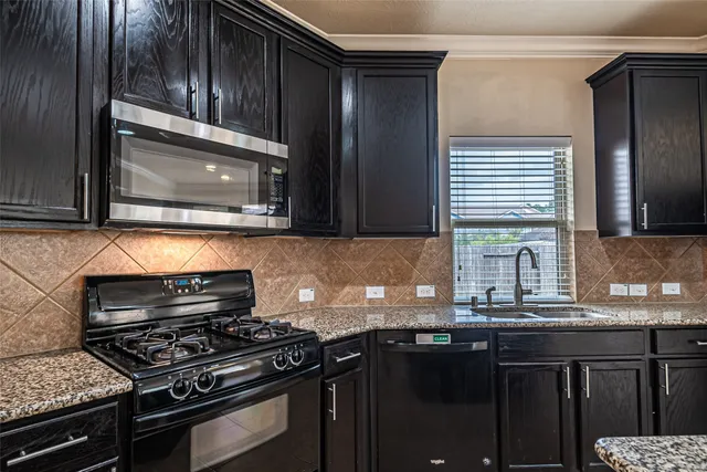a kitchen with granite countertop a stove sink and cabinets