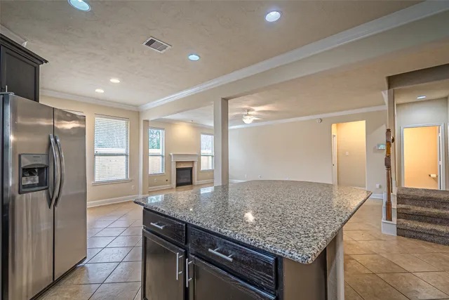 a kitchen with granite countertop a refrigerator and wooden cabinets
