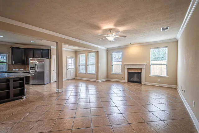 a view of an empty room with kitchen and fireplace