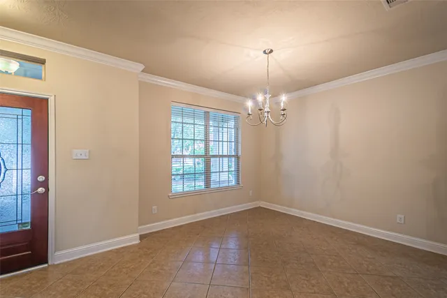 an empty room with chandelier fan and windows