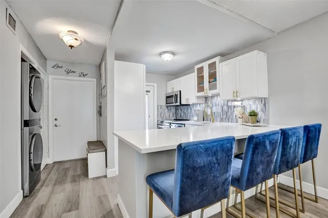 a kitchen with stainless steel appliances granite countertop a table chairs a refrigerator and cabinets