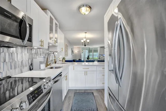 a kitchen with stainless steel appliances granite countertop a refrigerator a sink and white cabinets