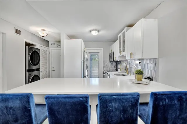 a kitchen with stainless steel appliances a dining table chairs and white cabinets