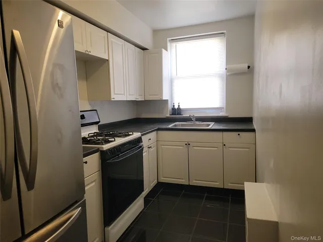 a kitchen with granite countertop a sink stove and refrigerator