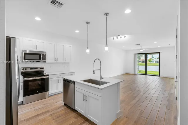 a kitchen with stainless steel appliances granite countertop a sink a stove and a wooden floors