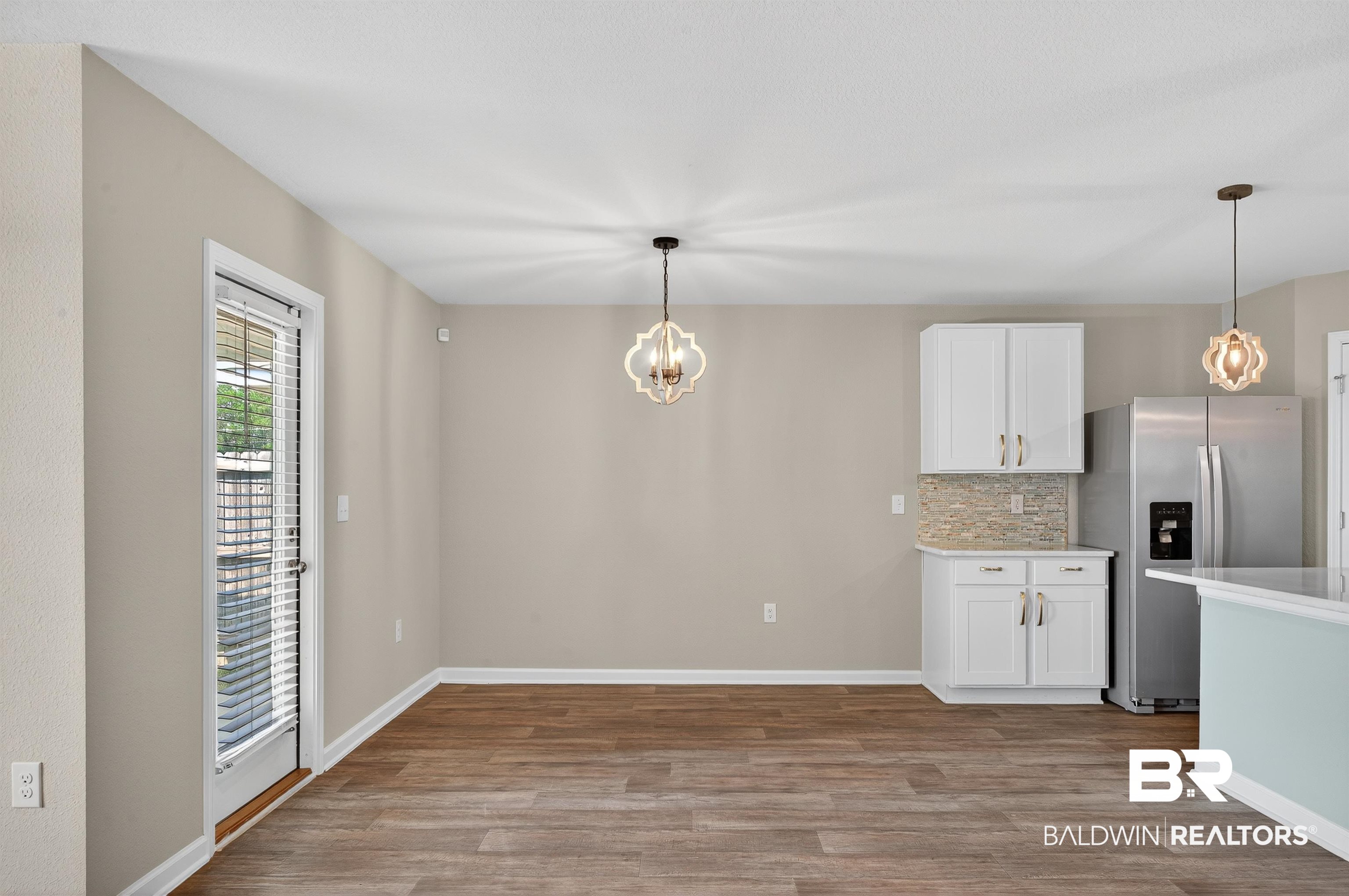7429 Brompton Drive Foley, AL 36535 - Photo 13 of 50 Kitchen with stainless steel fridge with ice dispenser, tasteful backsplash, a chandelier, and white cabinetry