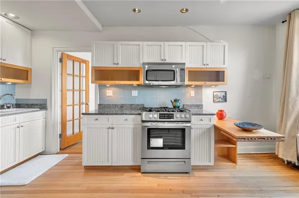 a kitchen with stainless steel appliances granite countertop a stove a sink dishwasher and a microwave oven with wooden floor
