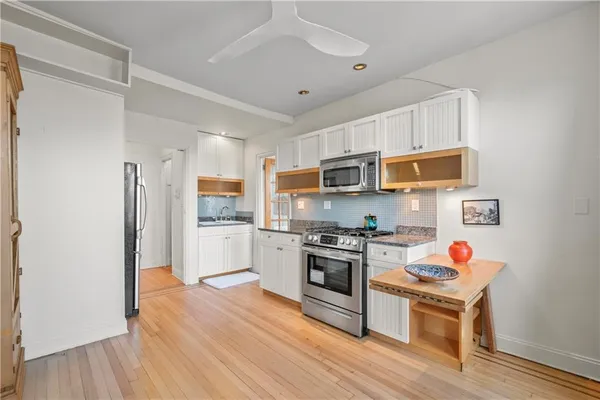 a kitchen with stainless steel appliances granite countertop a stove top oven a refrigerator a sink and dishwasher with wooden floor