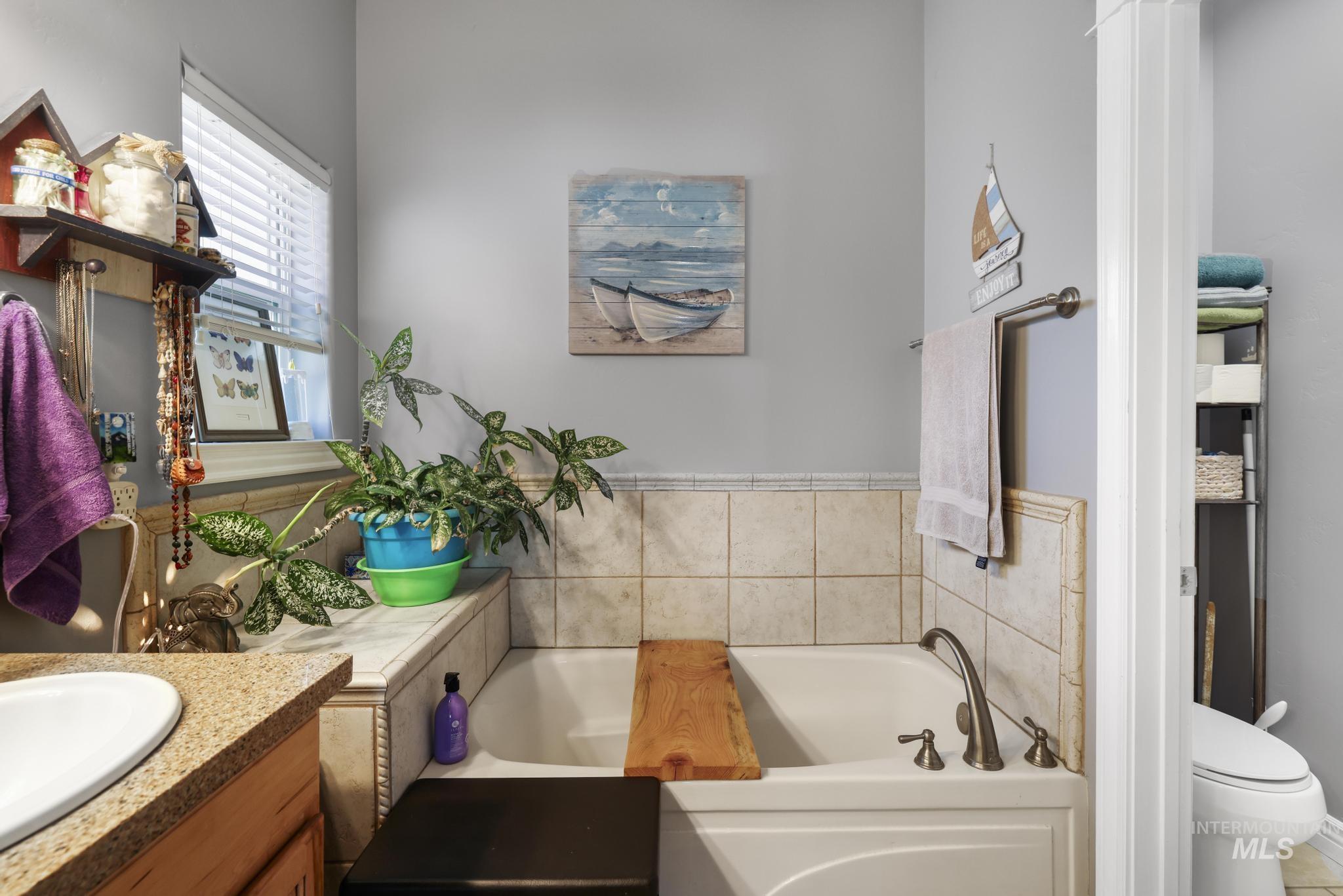 467 Wildrose Loop Twin Falls, ID 83301 - Photo 26 of 46 White drop-in bathtub with bronze fixtures, surrounded by light-colored tile