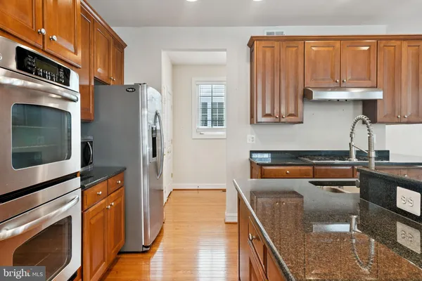 a kitchen with a sink stove and wooden floor
