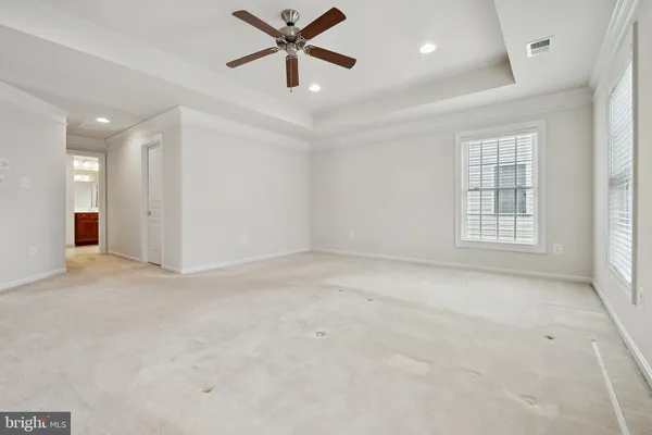 an empty room with chandelier fan and windows