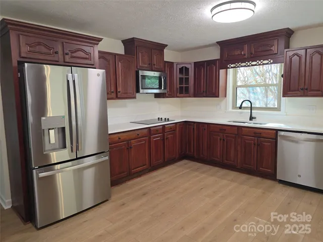 a kitchen with stainless steel appliances granite countertop a refrigerator a stove a sink and a microwave