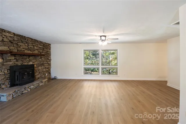an empty room with windows and fireplace