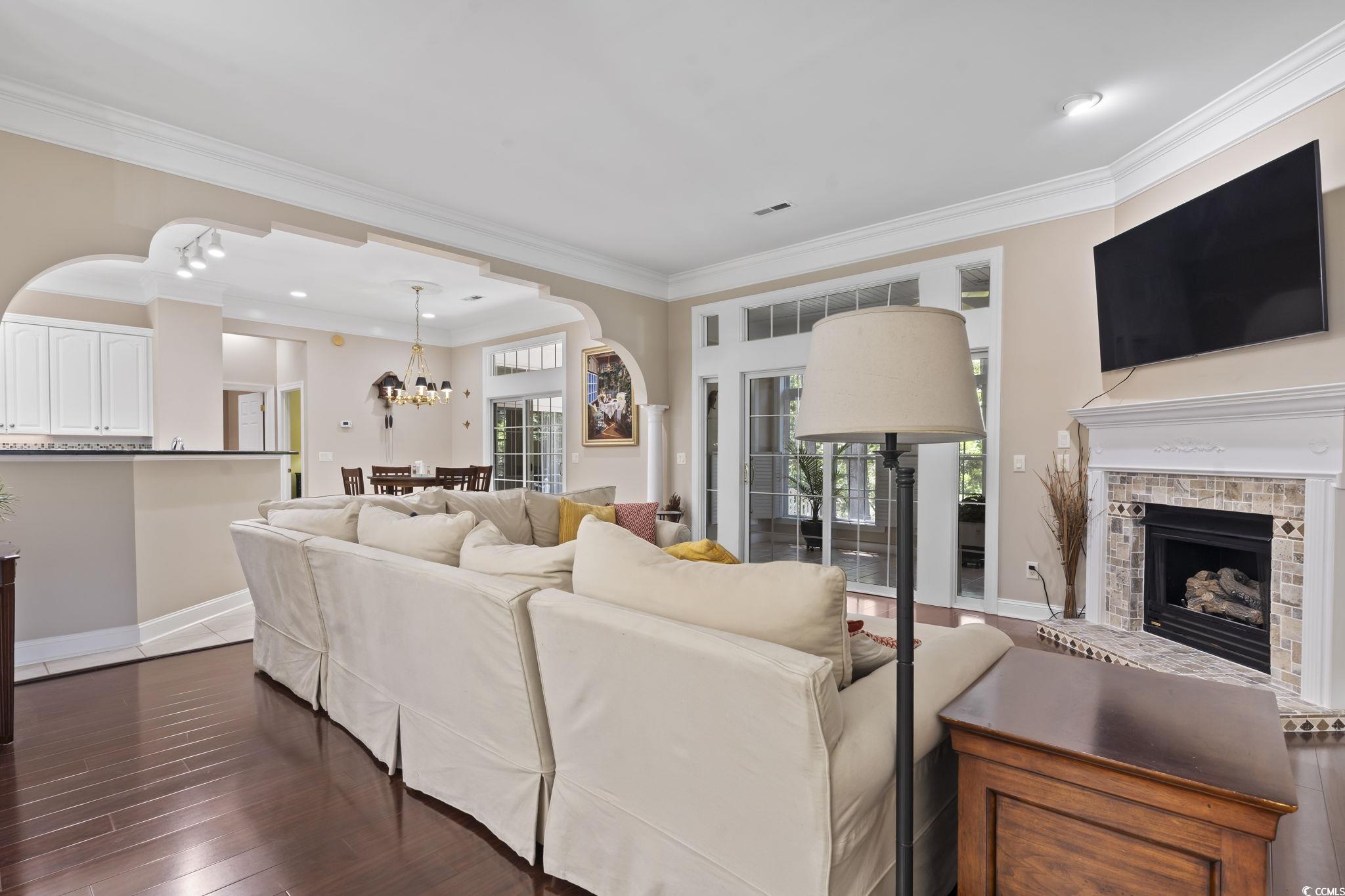 4495 Trotters Court Murrells Inlet, SC 29576 - Photo 18 of 29 Living area featuring plenty of natural light, a fireplace with raised hearth, crown molding, a chandelier, and arched walkways