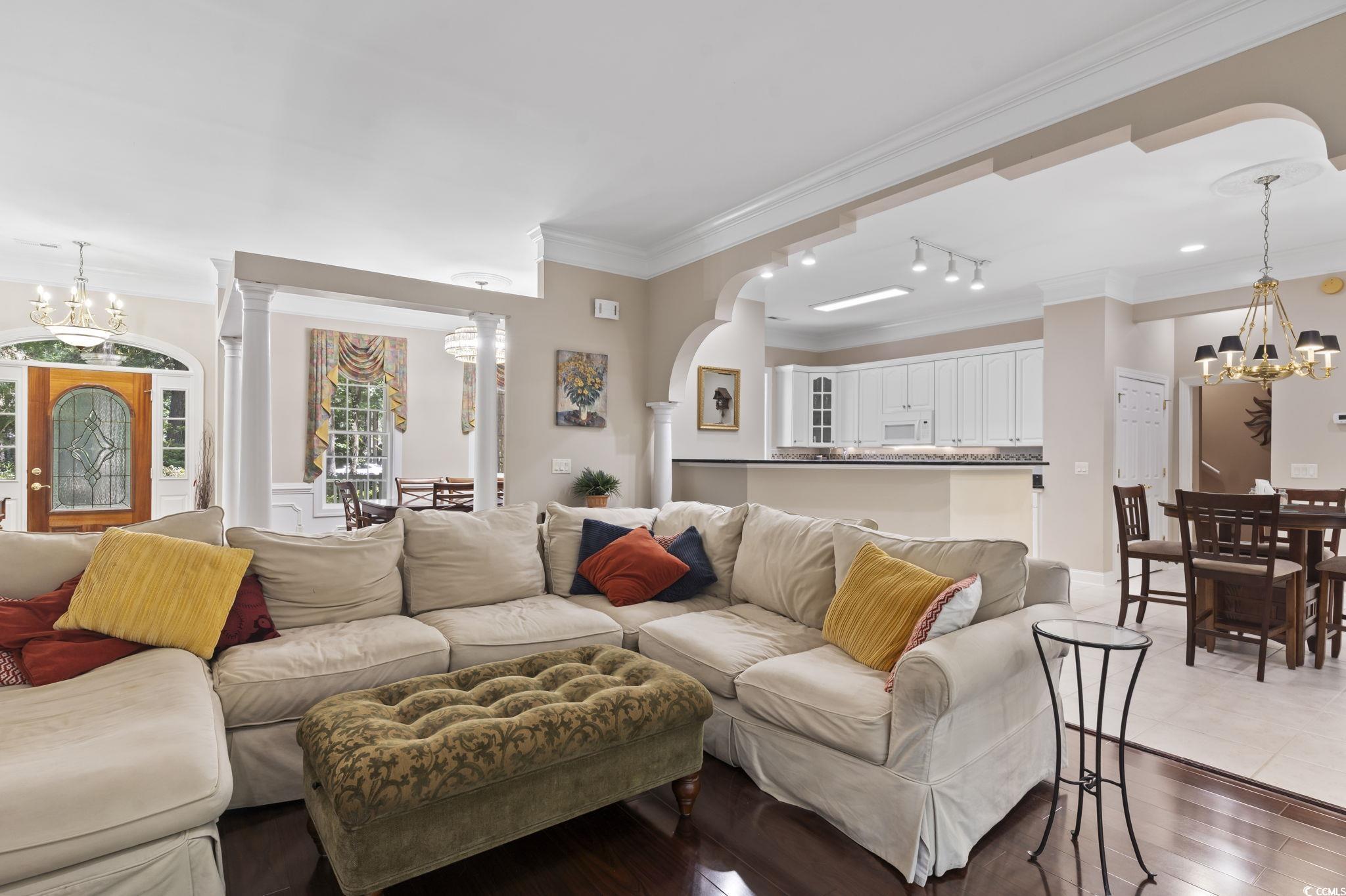 4495 Trotters Court Murrells Inlet, SC 29576 - Photo 22 of 29 Living area with a chandelier, crown molding, ornate columns, arched walkways, and dark wood-type flooring