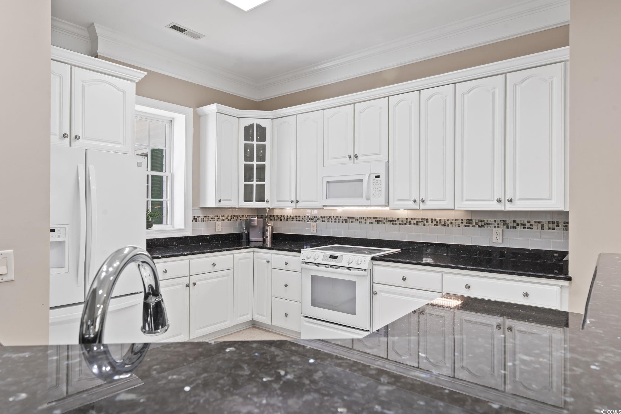 4495 Trotters Court Murrells Inlet, SC 29576 - Photo 23 of 29 Kitchen featuring white appliances, dark stone counters, white cabinetry, tasteful backsplash, and crown molding